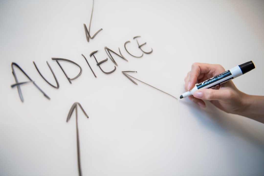 Woman's hand writing the word "audience" on a whiteboard, with arrows.